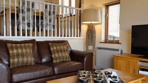 A living room with a brown leather sofa, a wooden coffee table, a lamp, and a television. - 1 bedroom accommodation in Llanaber, near Barmouth (Llanaber, near Barmouth)