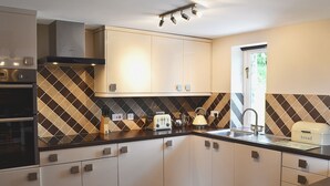 Een moderne keuken met een ingebouwde oven, een waterkoker en een broodmachine op het aanrecht.