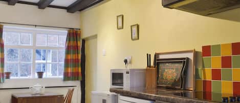 Una cocina con techo de madera, una ventana con cortinas, microondas, refrigerador y estufa.
