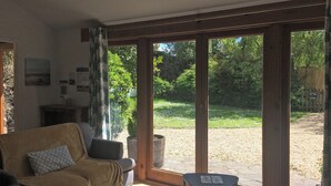 Un soggiorno con divano, un tavolino e vista su un giardino attraverso ampie vetrate.