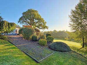 A well-maintained garden with a variety of shrubs and a lawn, a wooden pergola, and a large tree providing shade. - 3 bedroom accommodation in Uplowman, near Tiverton (Uplowman, near Tiverton)