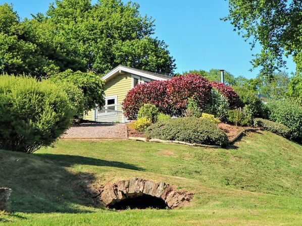 Una casa con un césped cuidado, un pequeño camino de entrada y una estructura de piedra al frente.