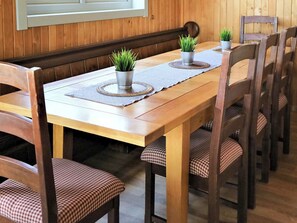 Ein Holztisch mit zwei Blumentöpfen, karierten Stühlen und einer gewebten Tischmatte.
