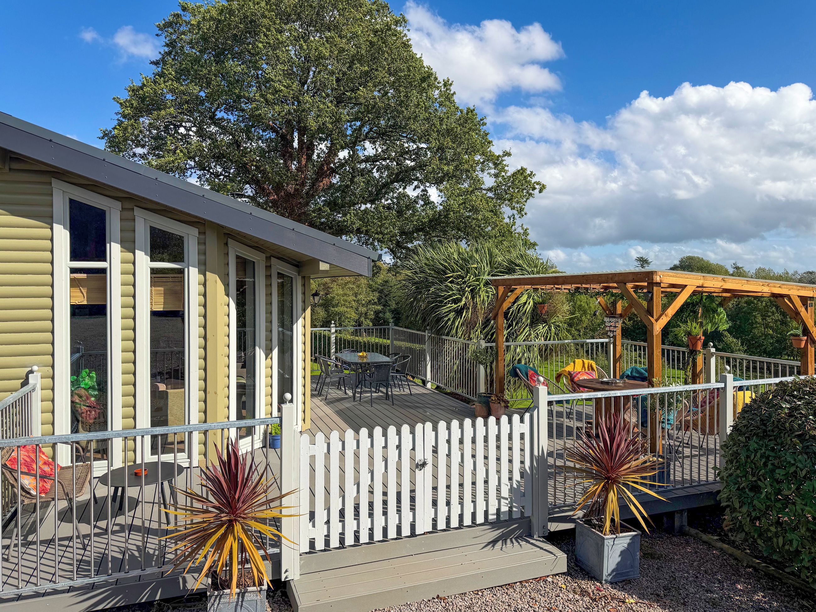 A house with a deck, a pergola, and a white picket fence.