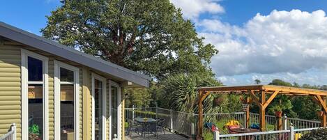 A house with a deck, a pergola, and a white picket fence.