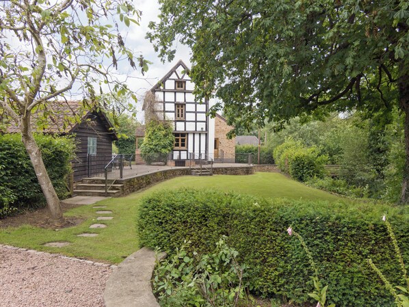 A traditional half-timbered house with a stone staircase leading to a wooden deck.