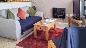 Ein modernes Wohnzimmer mit einer Couch, einem Couchtisch, einem Fernseher und einem kleinen Holznachttisch.