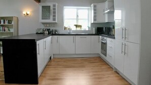 A modern kitchen with white cabinets, a black countertop, and a wooden floor. - 2 bedroom accommodation in Ludlow (Ludlow)