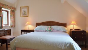 Una camera da letto con un letto, due comodini, una panca, una finestra con tende e un quadro appeso al muro.