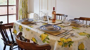 Un tavolo da pranzo apparecchiato con piatti, bicchieri e una bottiglia, in una stanza con una finestra e tende.