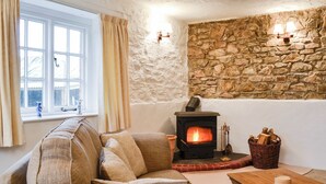 A cozy living room with a stone wall, a fireplace, a sofa, and a table. - Cider Cottage - E5576 (Chittlehampton, near Umberleigh)