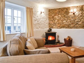 A cozy living room with a stone wall, a fireplace, a sofa, and a table. - Cider Cottage - E5576 (Chittlehampton, near Umberleigh)