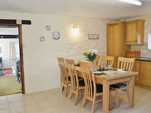Un coin repas avec une table et des chaises en bois, un vase de fleurs et une horloge murale.