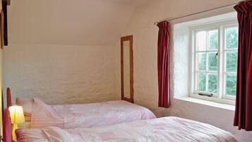 Un dormitorio con dos camas, una ventana con cortinas y una lámpara.