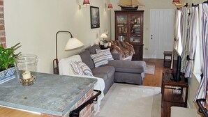 A cozy living room with a brick fireplace, a grey sofa, a wooden cabinet, and a striped curtain. - 2 bedroom accommodation in Washaway, near Bodmin (Washaway, near Bodmin)