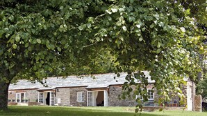 A stone building with multiple windows and doors, surrounded by a grassy area. - 2 bedroom accommodation in Washaway, near Bodmin (Washaway, near Bodmin)