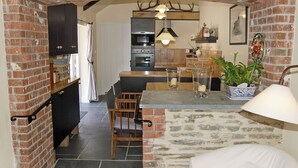 A kitchen with a brick archway, wooden furniture, and a hanging light fixture. - 2 bedroom accommodation in Washaway, near Bodmin (Washaway, near Bodmin)