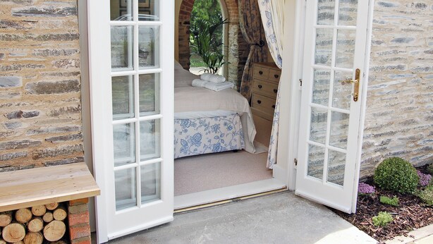 A cozy room with a bed, a dresser, and a window with curtains. - 2 bedroom accommodation in Washaway, near Bodmin (Washaway, near Bodmin)