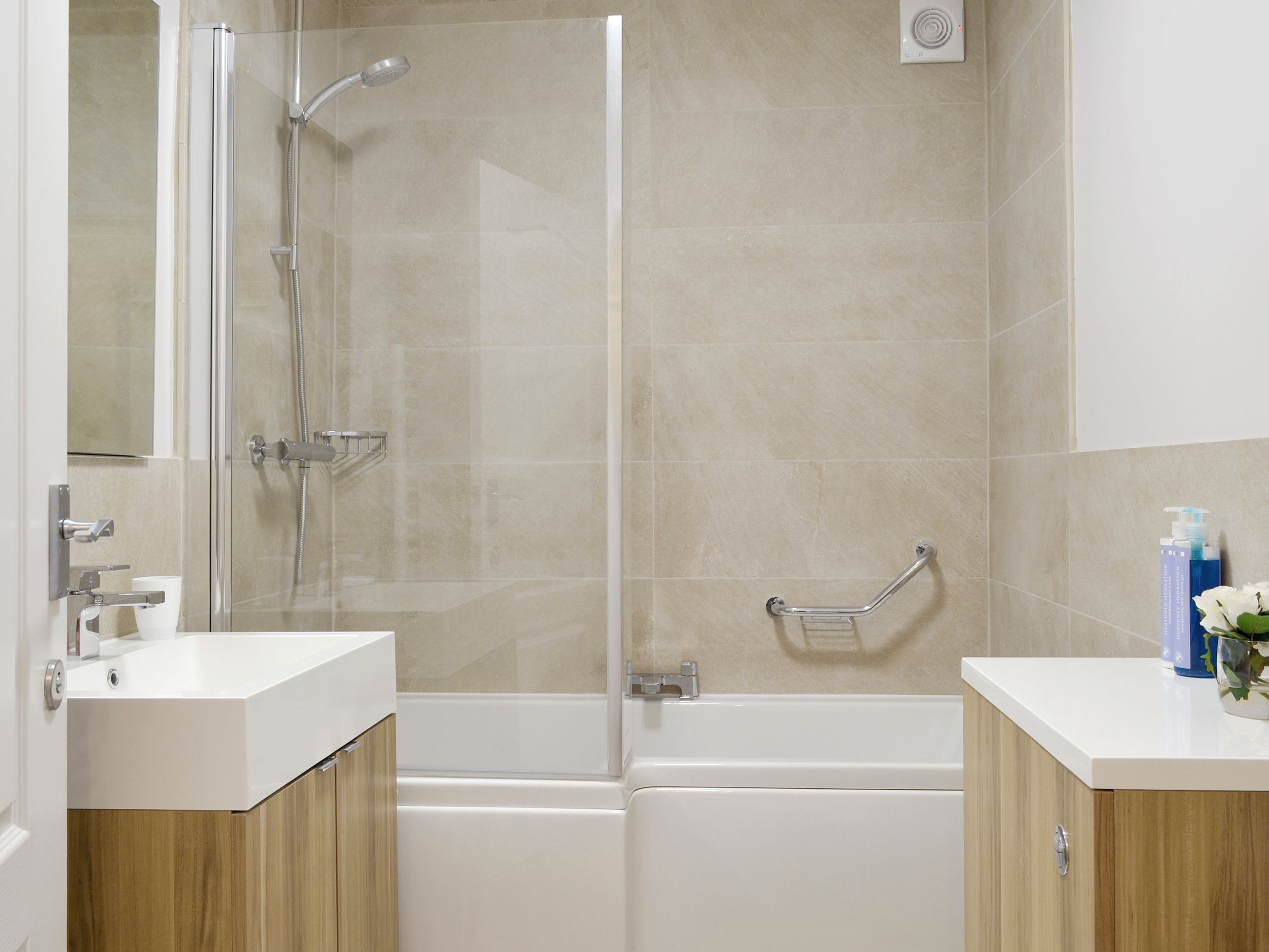 A modern bathroom with a glass-enclosed shower, a white bathtub, and wooden cabinetry.