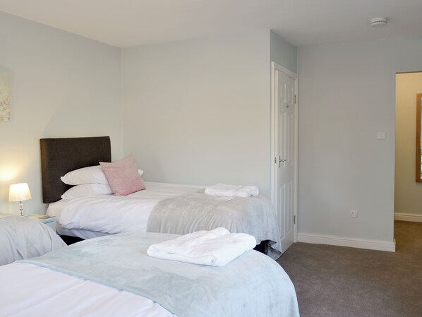 Une chambre d’hôtel avec deux lits, une table de chevet, une lampe et une porte.