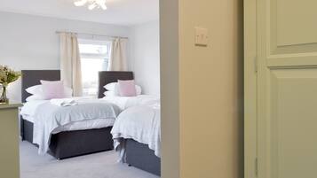 A bedroom with two beds, a nightstand, a window with curtains, and a ceiling light.