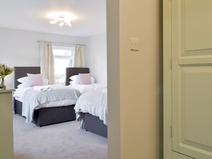 A bedroom with two beds, a nightstand, a window with curtains, and a ceiling light. - 5 bedroom accommodation in Bakewell (Bakewell)