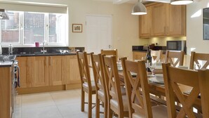 Una cocina moderna con armarios de madera, una isla central y una zona de comedor con sillas de madera.