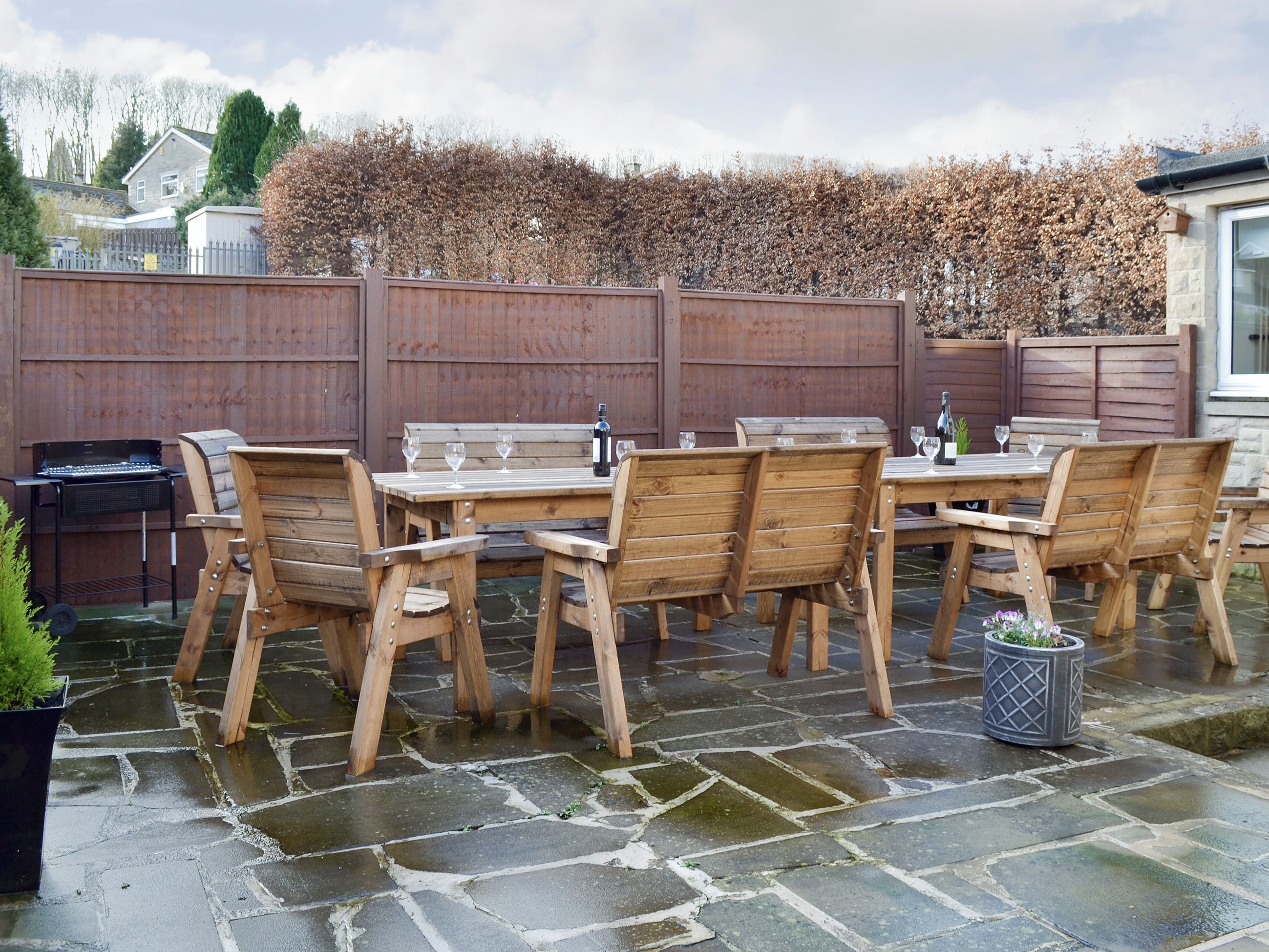 An outdoor patio with wooden furniture and a grill.