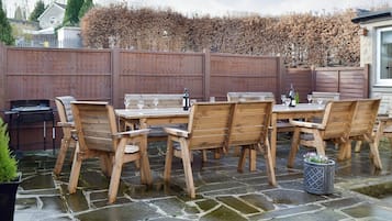 An outdoor patio with wooden furniture and a grill.
