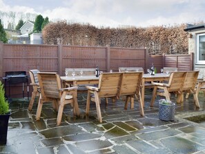 An outdoor patio with wooden furniture and a grill. - 5 bedroom accommodation in Bakewell (Bakewell)