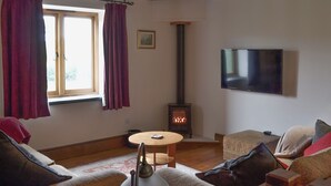 A cozy living room with a fireplace, a television, and comfortable seating. - 4 bedroom accommodation in Colyton (Colyton)