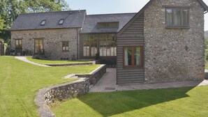 A stone house with a sloped roof, a stone staircase, and a well-maintained lawn. - 4 bedroom accommodation in Colyton (Colyton)