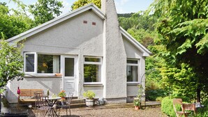 Une maison avec une façade en pierre, une cheminée et une allée gravillonnée.