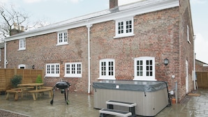 Una casa in mattoni con patio, barbecue e vasca idromassaggio.