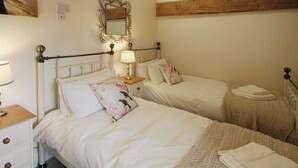 Camera da letto con due letti, un comodino con lampada, uno specchio e una trave in legno al soffitto.