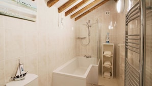 Un bagno con una vasca, il water e uno scaffale con asciugamani.
