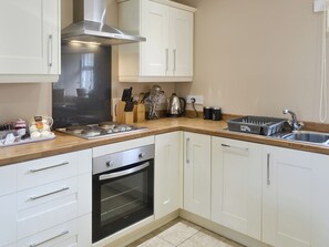 A modern kitchen with white cabinets, stainless steel appliances, and a wooden countertop.