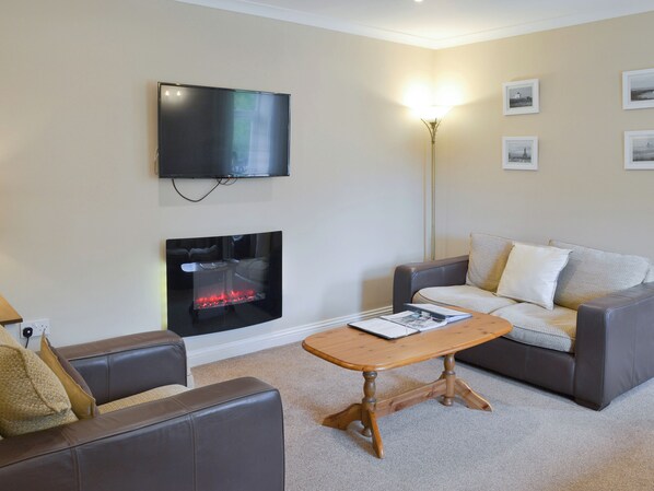 A living room with a flat-screen TV, a fireplace, a sofa, a coffee table, and a floor lamp.