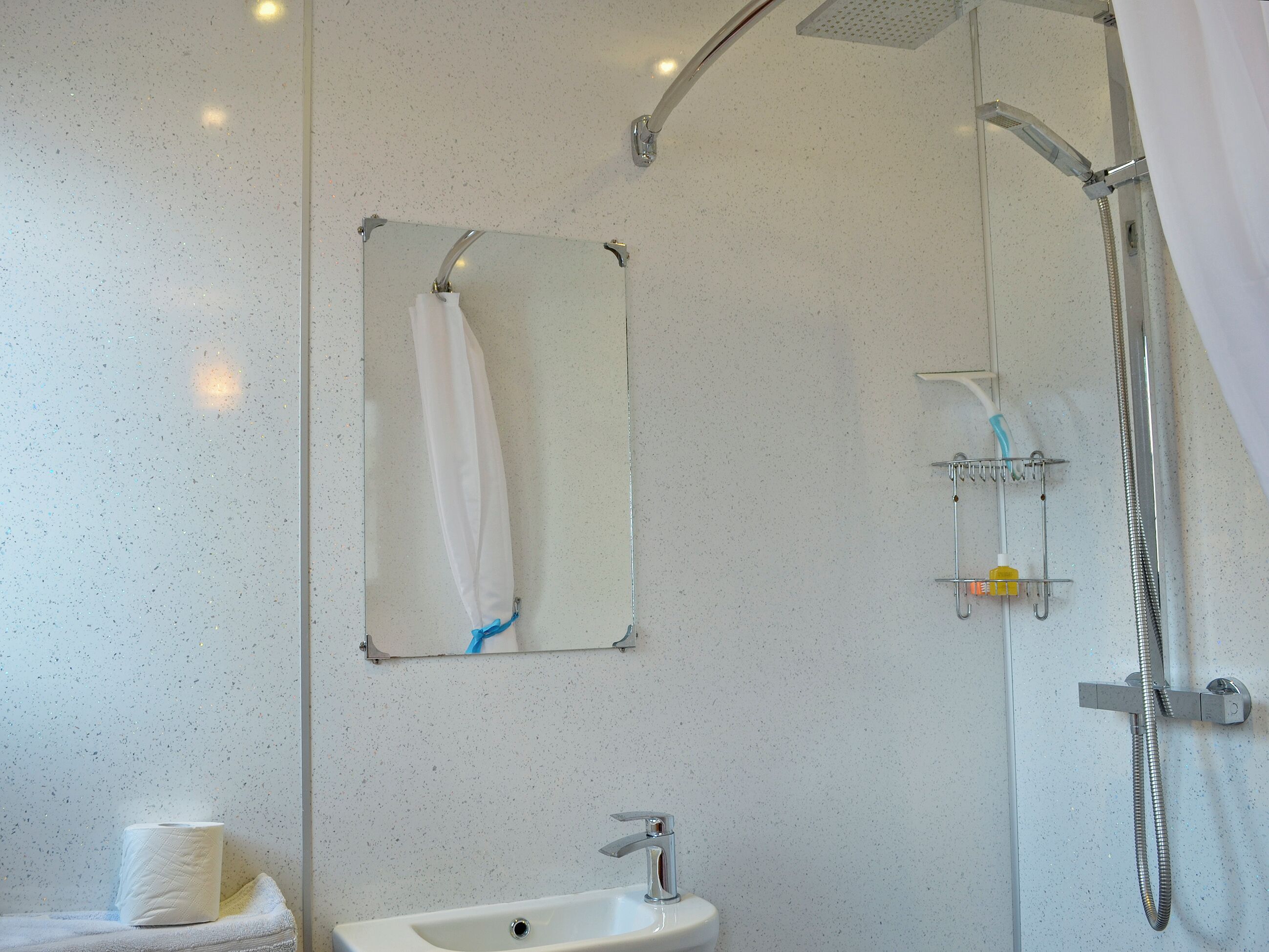 Un baño con lavamanos, espejo y ducha.