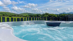 A hot tub with a view of green hills and a clear sky. - 2 bedroom accommodation in Llanllechid, near Bangor (Llanllechid, near Bangor)