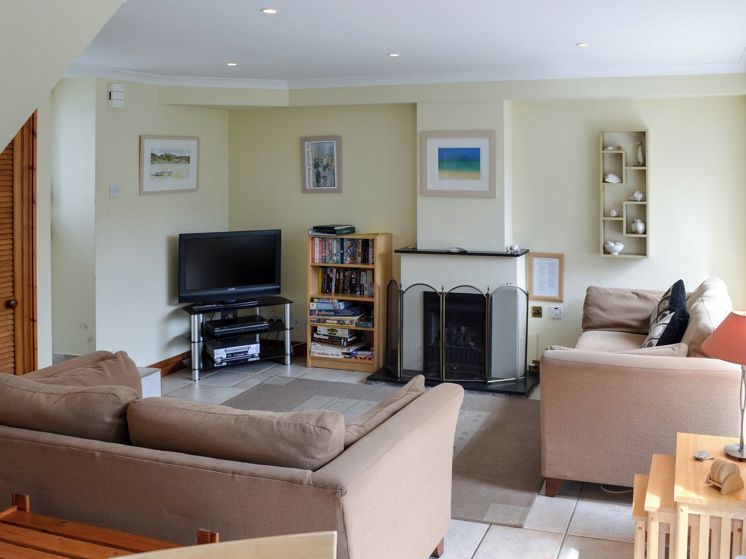 A living room with a TV, bookshelf, fireplace, and two sofas.