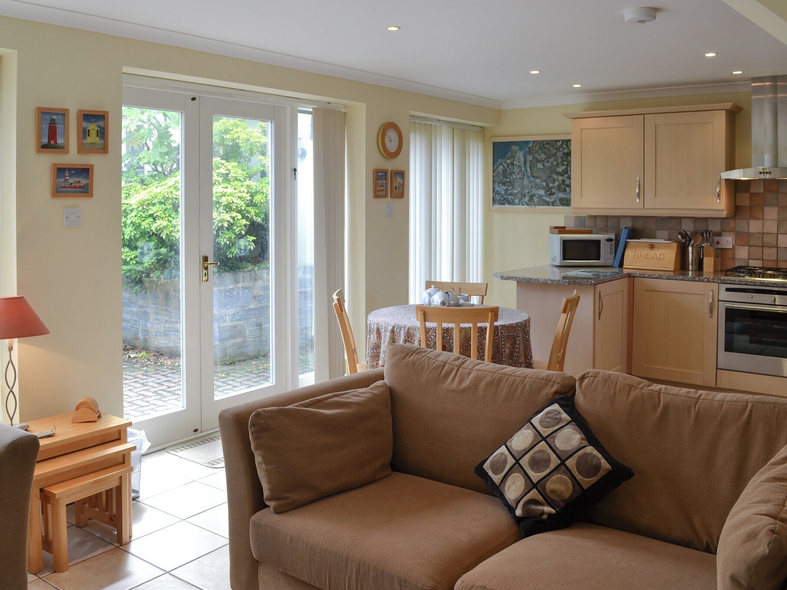A cozy living room with a sofa and a small table, a kitchen with cabinets and appliances, and a dining area with a table and chairs.