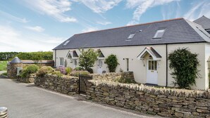 A two-story house with a stone wall and a sloped roof. - 1 bedroom accommodation in Padstow (Padstow)