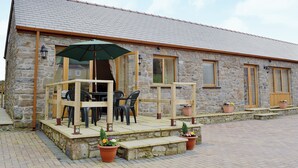 A stone building with a covered patio area, outdoor seating, and potted plants. - 2 bedroom accommodation in Carmarthen (Carmarthen)