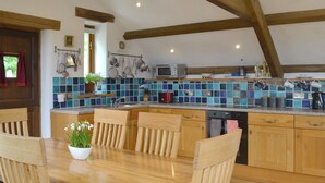 A kitchen with wooden cabinets, a tiled backsplash, and a dining area with a wooden table and chairs. - 2 bedroom accommodation in Ugborough, Ivybridge (Ugborough, Ivybridge)