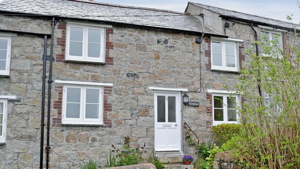 A stone building with multiple windows and a door, surrounded by greenery and a stone wall. - 2 bedroom accommodation in Charlestown, St Austell (Charlestown, St Austell)