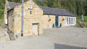 A stone building with a blue door and windows, surrounded by gravel and trees. - Bickley School Annexe (Bickley, near Langdale End)