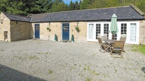 A stone building with a gravel courtyard, a wooden table and chairs, and a green umbrella. - Bickley School Annexe (Bickley, near Langdale End)