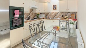A modern kitchen with a skylight, stainless steel appliances, and a glass dining table. - Bickley School Annexe (Bickley, near Langdale End)