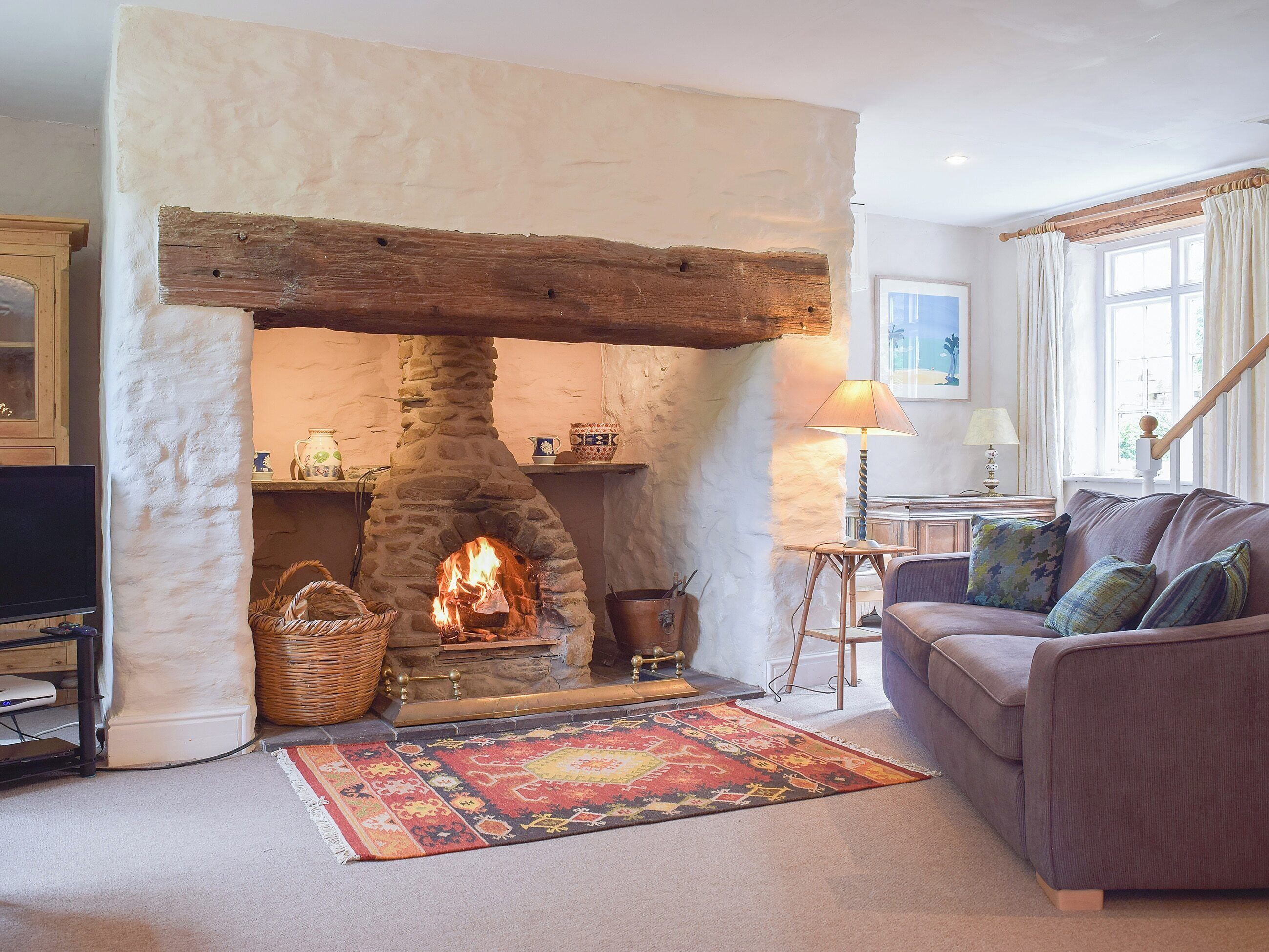 A cozy living room with a stone fireplace, a comfortable sofa, and a decorative rug.